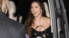 a woman in a black dress is smiling while holding a bag