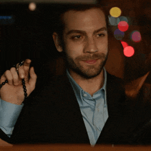 a man in a suit and blue shirt is holding a rosary