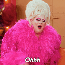 a drag queen is wearing a pink feather boa and says ohhh