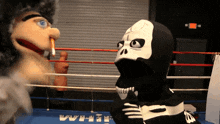 a puppet and a skeleton are in a boxing ring and the puppet is smoking a cigarette