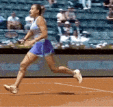 a woman is running on a tennis court holding a racket