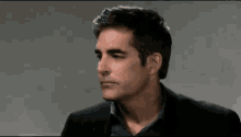 a man in a suit and a blue shirt is looking at the camera .