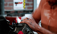 a shirtless man is working on a machine in a garage