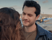 a man in a leather jacket looks at a woman