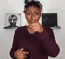 a woman is pointing at the camera while wearing a headband and a ring .