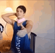 a man wearing a blue tank top with the word revolution on it giving a thumbs up .