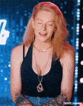 a woman wearing a black tank top and a gold necklace is smiling