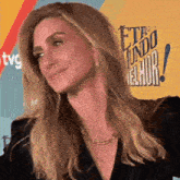 a woman in a black jacket is smiling in front of a sign that says eto mundo melhor .