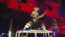 a man playing a bass guitar on a stage with the letter d on the bottom right