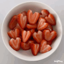 a white bowl filled with sliced strawberries in the shape of a heart