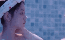 two women are looking at each other in a bathtub . one of the women is wearing a towel on her head .