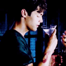 a man with a tattoo on his wrist is holding a martini glass .