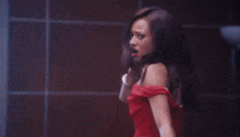 a woman in a red dress is standing in front of a wall .