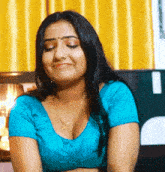 a woman wearing a blue blouse with a necklace around her neck