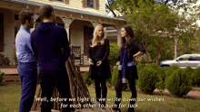 a group of people standing in front of a house with a man saying well before we light it we write down our wishes for each other