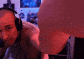 a man wearing headphones looks at the camera with a purple background