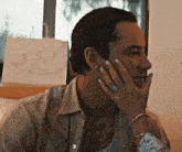 a man is sitting at a table with his hand on his face and a woman is touching his face .