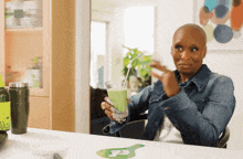 a woman sitting at a table drinking a green smoothie with a straw
