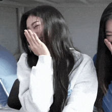 a woman with long black hair is laughing with her hands over her mouth