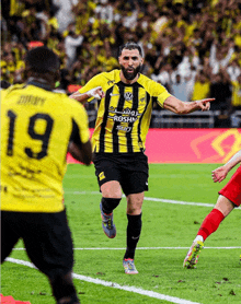 a soccer player wearing a yellow and black jersey with the number 19 on it