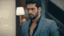 a man with a beard is wearing a suit and standing in a room .