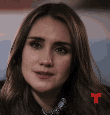 a close up of a woman 's face with a red t in the background