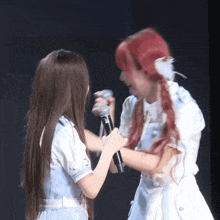 a girl with red hair holds a microphone next to another girl with long hair