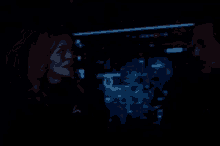 a man and a woman are standing next to each other in a dark room in front of a screen .