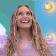a woman in a purple shirt is smiling and looking up at something