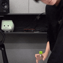 a person holding a bottle with a green cap in front of a speaker that says jbl on it