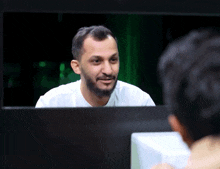 a man with a beard is looking at his reflection in a mirror