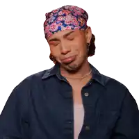a man wearing a denim jacket and a floral headband is making a sad face