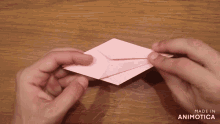 a person holding a piece of pink paper with the words made in animotica on the bottom right