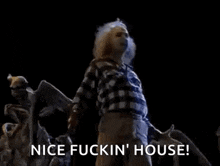 a man in a plaid shirt is giving a thumbs up in front of a statue of a skeleton .