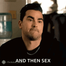 a man is making a face and saying `` and then sex '' while wearing a black shirt .