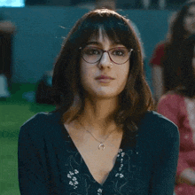 a woman wearing glasses and a horseshoe necklace
