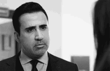 a man in a suit and tie is looking at a woman in a mirror .