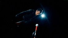 a man in a black suit is holding a red microphone