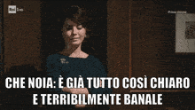 a woman stands in front of a wooden wall with the words che noia e gia tutto così chiaro e terribilmente banale