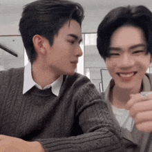 two young men are sitting next to each other and smiling at the camera