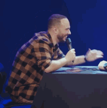 a man sitting at a table with a microphone in his hand