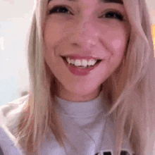 a woman is smiling and looking at the camera while wearing a white shirt .