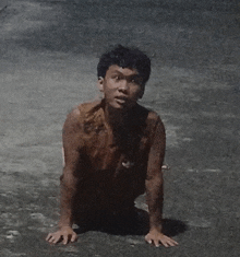 a young man is crawling on the ground with his hands on his knees .