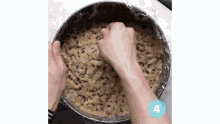 a person is pressing a cookie dough in a pan with a plastic wrap around it .
