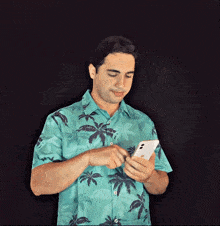 a man in a hawaiian shirt is looking at his cell phone