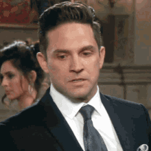 a man in a suit and tie stands in front of a woman .