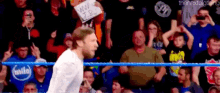 a man with a mask on his face is in a wrestling ring holding a sign that says ww jp