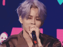 a young man with purple hair is singing into a microphone .