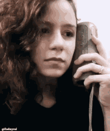 a woman with curly hair is talking on a cell phone .