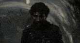 a man with blood on his face is standing in the dark looking at the camera .